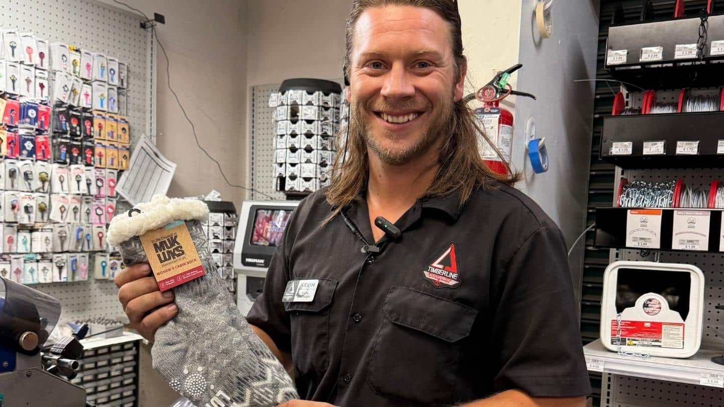 Timberline Ace team member holding cozy Muk Luks fuzzy socks for a holiday gift idea