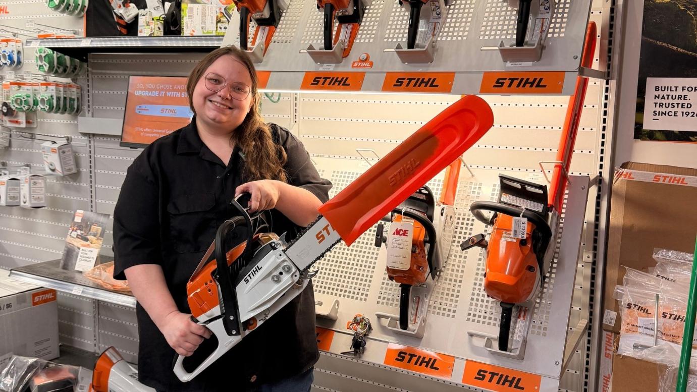 Timberline Ace team member holding a STIHL chainsaw in the store's STIHL equipment section