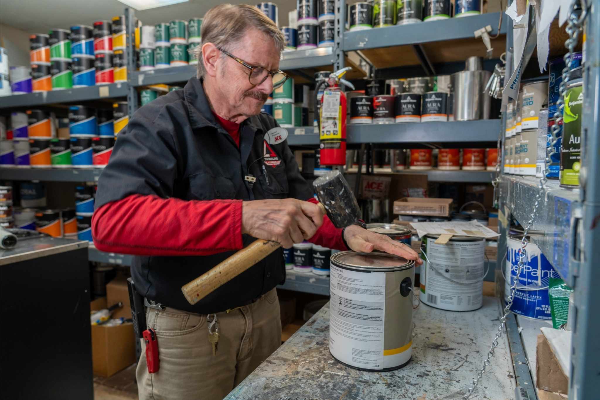 timberline ace employee working on paint can with hammer