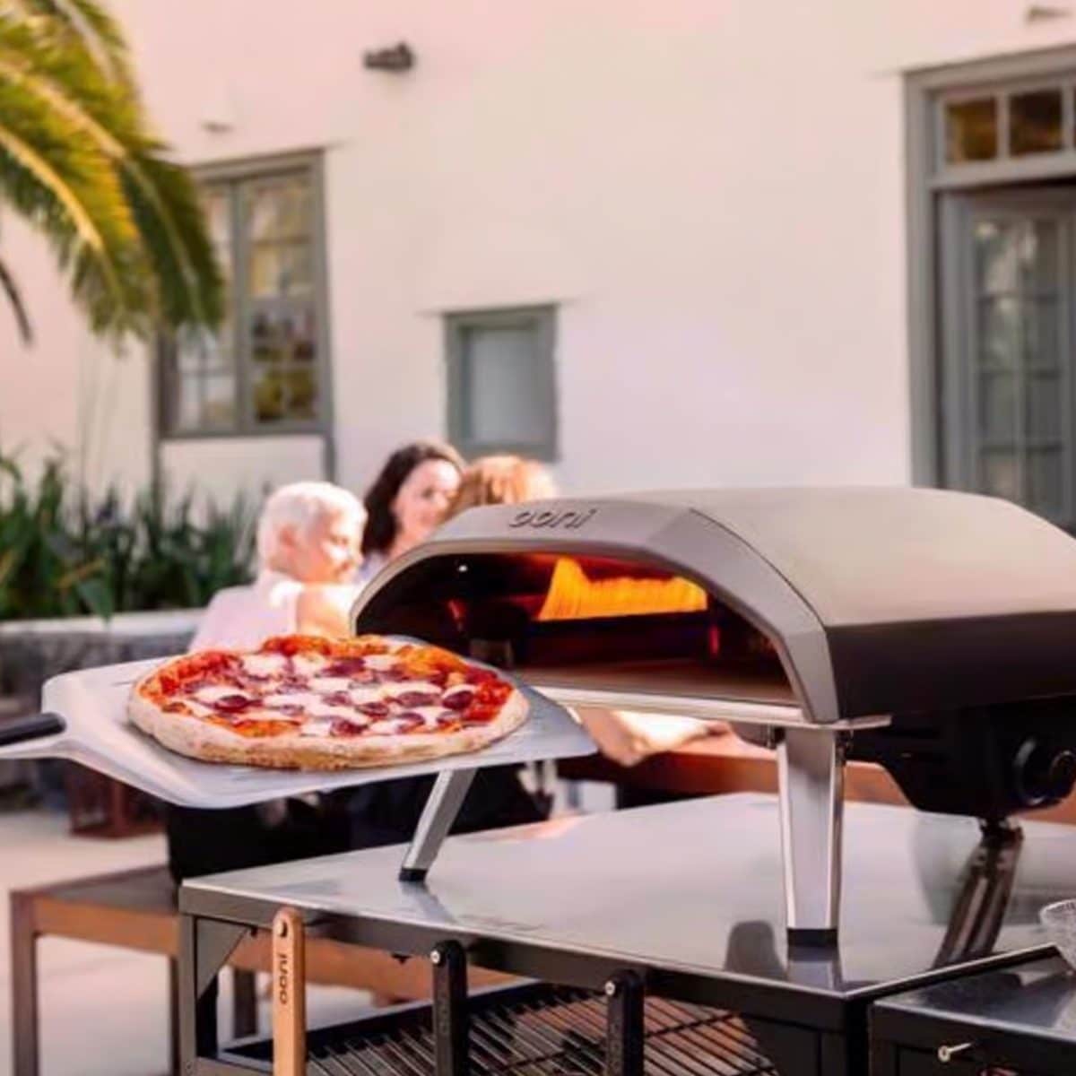 Outdoor pizza oven cooking pizza on backyard patio grill setup