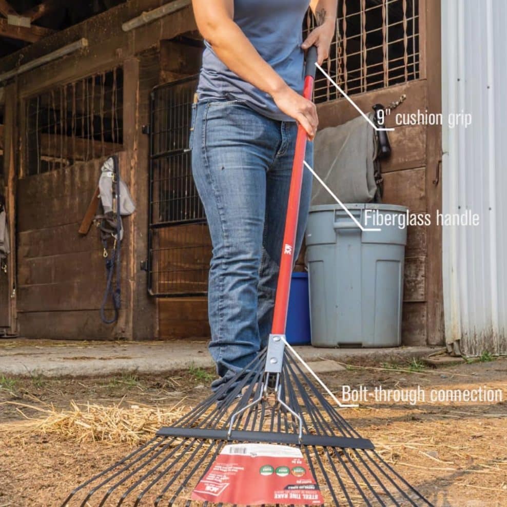 Person using metal rake to clean yard and gather debris