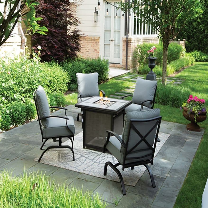 Outdoor patio seating area with fire pit table and cushioned chairs in backyard setting