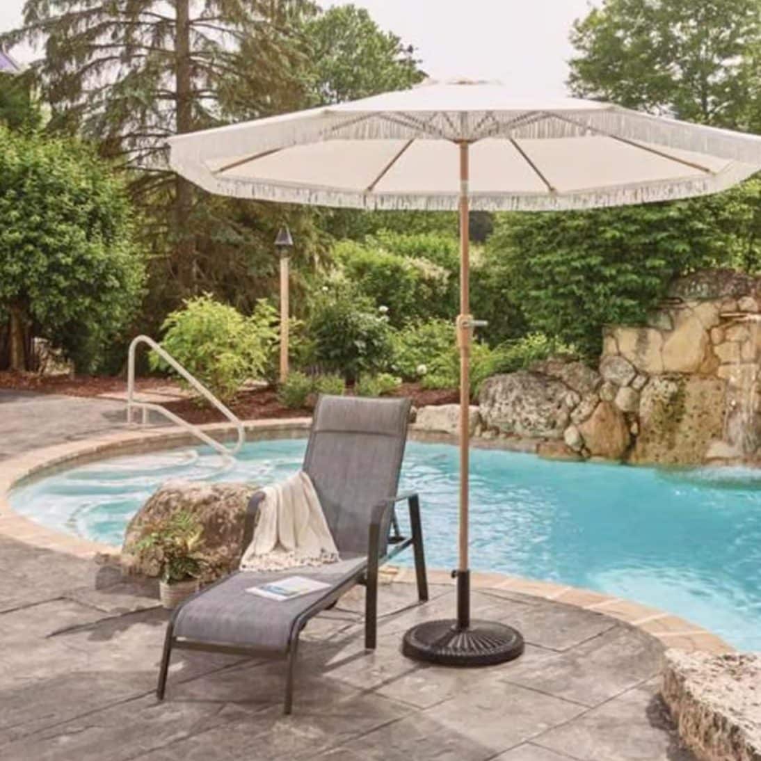 Patio umbrella shading lounge chair next to backyard pool